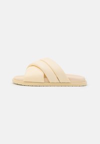 Korsbands-sandaler i mjukt gult material, med platt sula och rund tådesign samt texturerad undersida för bra grepp.