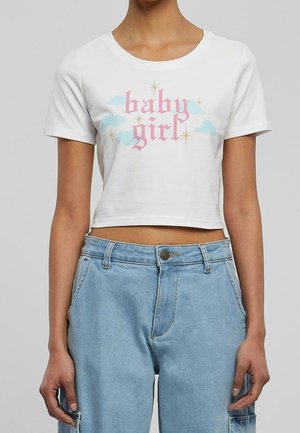 Camiseta blanca corta con "baby girl" en fuente gótica rosa, nubes azules y estrellas doradas, combinada con vaqueros de tiro alto en azul claro.