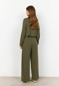 Ensemble deux pièces ample de couleur vert olive, comprenant un pantalon à jambes larges et un haut à manches longues. Tissu doux avec une texture lisse.