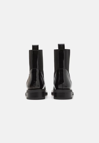 Botas ankle de pele brilhante preta com painéis laterais elásticos, acabamento suave e um pequeno salto em bloco. Design simples e elegante com laços para puxar.