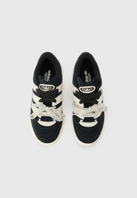 Black and cream sneakers with a textured suede upper, three horizontal stripes, and patterned laces. Includes a logo on the tongue.