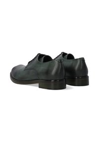 Donkergroene leren schoenen met een gladde textuur, vetersluiting en een lage, ronde hak. De neus heeft een contrasterende glanzende afwerking.