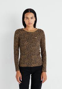 Dugi rukav majica s uzorkom leopard printa u smešnim i crnim bojama. Ima okrugli izrez i uski kroj. Napravljena je od mekanog materijala.