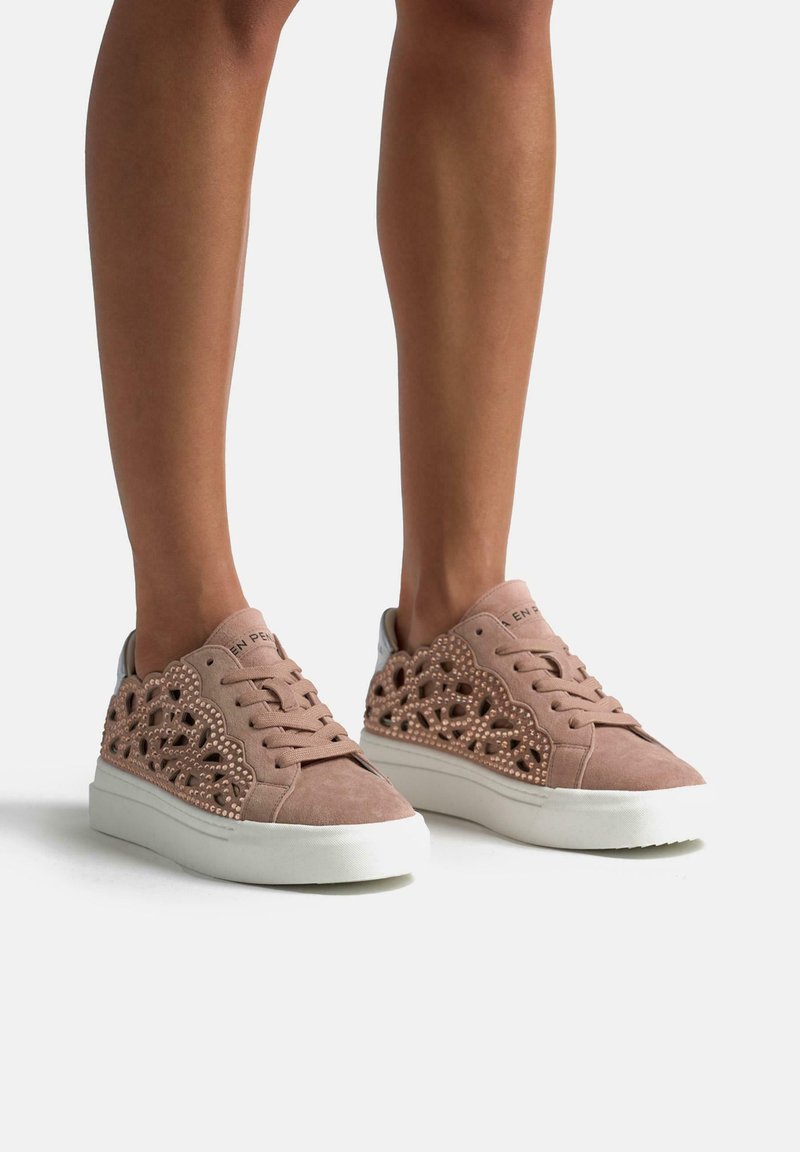 Sneaker rosa in suede con design perforato, dettagli testurizzati e suole in gomma bianca. Lacci e marchio visibili sulla linguetta.