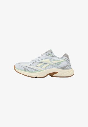 Witte en lichtgrijze hardloopschoen met beige en mintgroene accenten, ademend bovenwerk, gevoerde kraag en dikke off-white zool met bruin profiel.