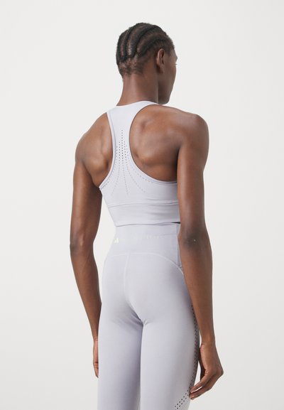 Világosszürke sportmelltartó, racerback dizájnnal, perforált részletekkel és testhez simuló siluettal. Reflektáló márkázással kiemelve.