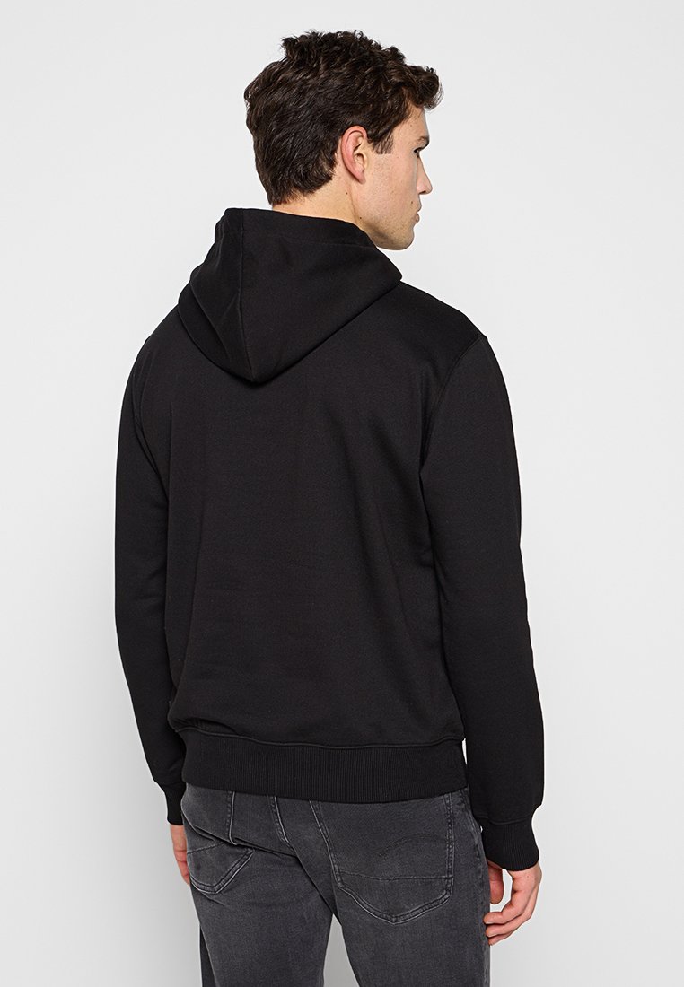 Sudadera negra con bolsillo tipo canguro, puños y dobladillo acanalados. Presenta una gran capucha trasera, hecha de una tela suave con una textura lisa.