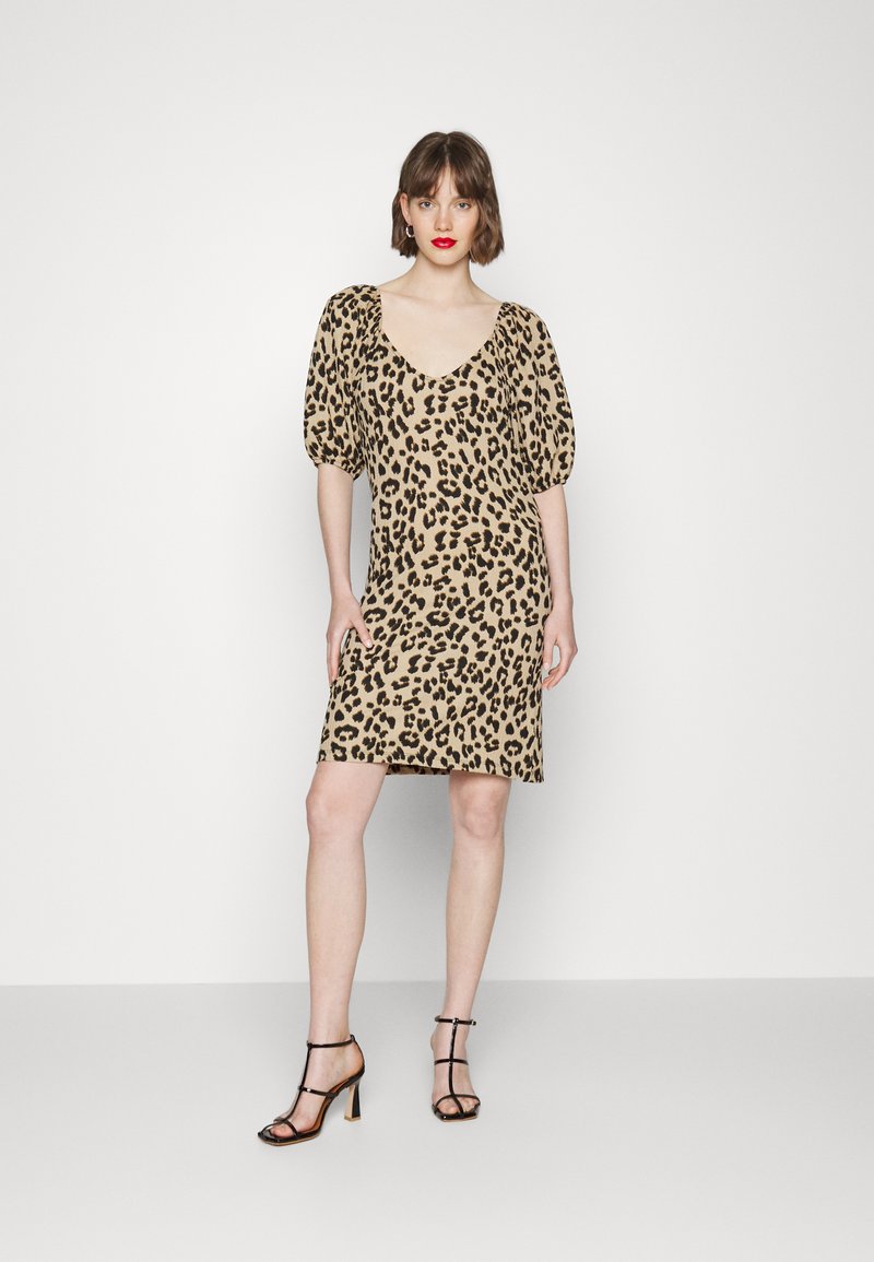 Vestido de estampado de leopardo em bege e preto; mangas curtas volumosas; decote em V profundo; até ao joelho; usado com saltos altos pretos com tiras. Textura suave.