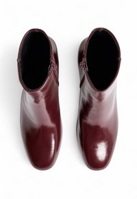 Botas de tobillo de cuero burdeos con un acabado brillante, cremalleras laterales y punteras redondeadas, con una textura suave y sin patrones visibles.