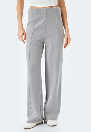 Pantalones grises de pierna ancha hechos de una tela texturizada, con costuras verticales, una cintura alta y un acabado suave.