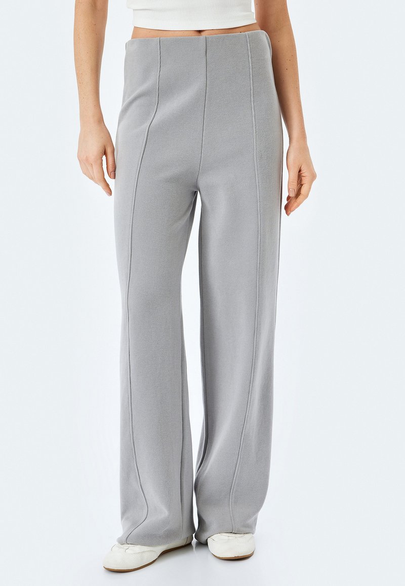 Pantalones grises de pierna ancha hechos de una tela texturizada, con costuras verticales, una cintura alta y un acabado suave.