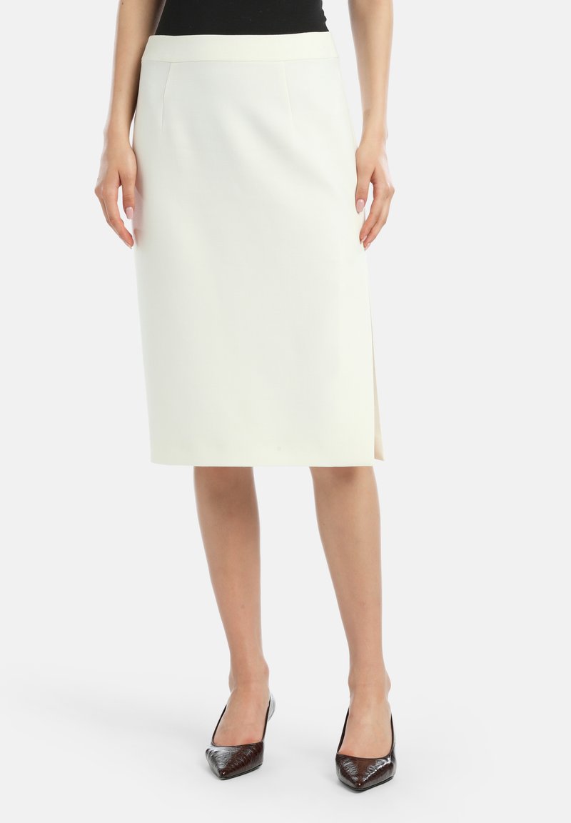 Valkoinen polven mittainen kynähame suoran leikkauksen kanssa, jossa on sivuvako ja sileä pinta, yhdistettynä tummaihoisiin teräväkärkisiin korkokenkiin.