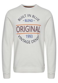 Felpa grigia chiaro con scollo rotondo, maniche lunghe e una grafica frontale nei colori blu, arancione e marrone scuro. Testo: "COSTRUITO IN BLU, ORIGINALE, 1993."