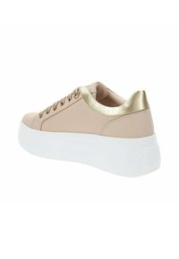 Sneaker beige con suola piatta bianca. Presenta un accento metallico dorato nel tallone e lacci funzionali. Texture in pelle liscia.