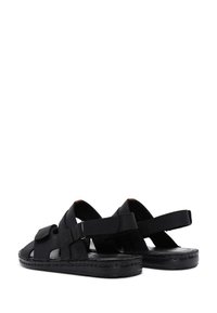 Sandalias negras con diseño de punta abierta, correas ajustables y una suela resistente. Hechas de material sintético, cuentan con detalles de costura.