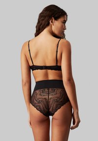 Set de lenjerie neagră din dantelă, format dintr-un sutien cu bretele reglabile și chiloți cu talie înaltă, prezentând modele complexe din dantelă și panouri solide.