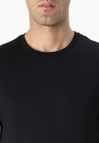 Camiseta de algodón negra con cuello redondo, mangas cortas y una textura suave, que muestra detalles de diseño mínimos y una forma ajustada.