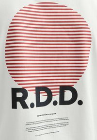 Hvidt stof med et stort rødt koncentrisk cirkelmønster med tynde striber. Sort fed tekst læser "R.D.D." og "ROYAL DENIM DIVISION" nedenfor.