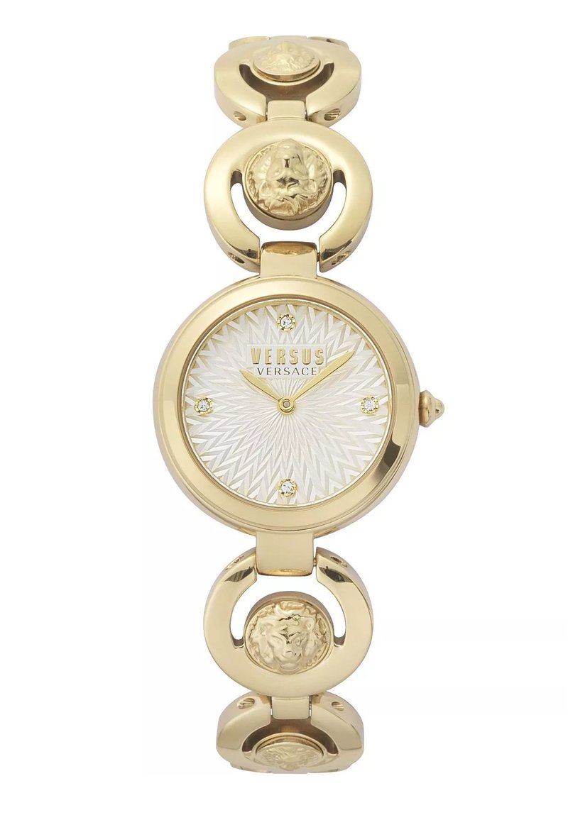 Reloj dorado con una esfera redonda, dial texturizado blanco y acentos de cristal. La correa presenta eslabones circulares y medallones en relieve.