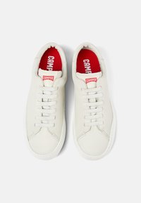 Weiße Leder-Sneaker mit niedrigem Design, ausgestattet mit einer roten Innensohle mit "CAMPER"-Markierung und hellgrauen Schnürsenkeln. Glatte Textur.