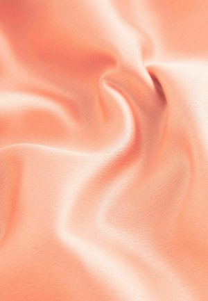 Tissu doux et lisse de couleur corail clair avec une texture légèrement brillante, drapé en vagues délicates, révélant un éclat subtil et une profondeur.