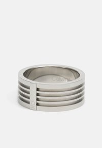 Metallring mit einer glatten, polierten Oberfläche, versehen mit vier horizontalen Kerben und einem vertikalen Akzent. Mit "CK" für das Branding gekennzeichnet.