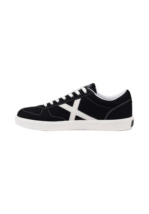 Zapatilla negra de caña baja con cordones blancos, suela blanca y un gran diseño blanco "X" en el lateral.