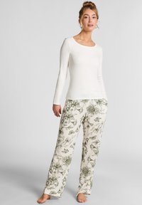 Wit longsleeve top gecombineerd met lichtgekleurde pyjamabroek met een groene bloemenpatroon. Zacht, soepel materiaal met een relaxte pasvorm.