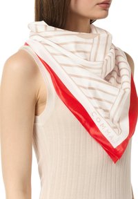 Seidenschal in Weiß mit beigen diagonalen Streifen und einem kräftigen roten Rand; hat eine glatte Textur und den Markennamen "COMMA" am Rand.