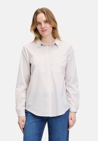 Striped button-up shirt in light fabric, featuring vertical stripes in pale colors, a collared neck, and two front pockets.