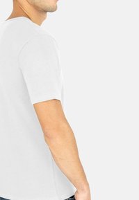 Weißes T-Shirt mit kurzen Ärmeln aus Baumwolle, in regulärer Passform und glatter Textur. Seitenansicht, die den Ausschnitt und die Ärmel Details zeigt.