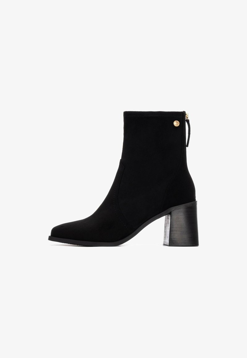 Stivale alla caviglia in suede nero con punta quadrata, chiusura con cerniera e tacco a blocco texturizzato. Presenta un accento dorato sul lato.