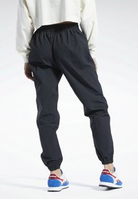 Mustat kevyet jumppahousut, joissa on joustava vyötärö ja joustavat hihnat, yhdistettynä monivärisiin retrolenkkareihin. Tekstuuri materiaali viimeistely.