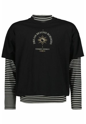 Sort cropped T-shirt lag-på-lag over sort og hvid stribet langærmet, med gyldent sol- og månegrafik og tekst "Dream Beyond Borders Cosmic Energy Garcia."