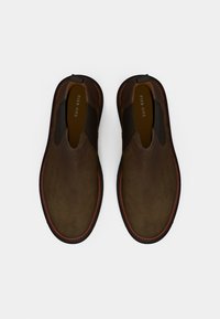 Pantofi slip-on maro, cu superior din zână, panouri elastice laterale și tălpi din cauciuc negru. Cusături detaliate de-a lungul marginii.