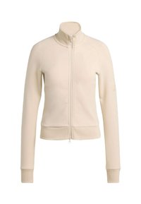 Chaqueta beige claro con cremallera hecha de un material suave. Cuenta con un cuello alto, mangas largas, puños acanalados y una cintura ajustada. Detalle sutil de logo.