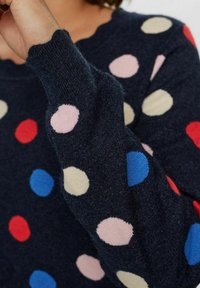 Mornarska jopica z okroglo izrezo in dolgimi rokavi, ki ima večbarvne pikice v roza, rdeči, modri in bež barvi na strukturirani tkanini.