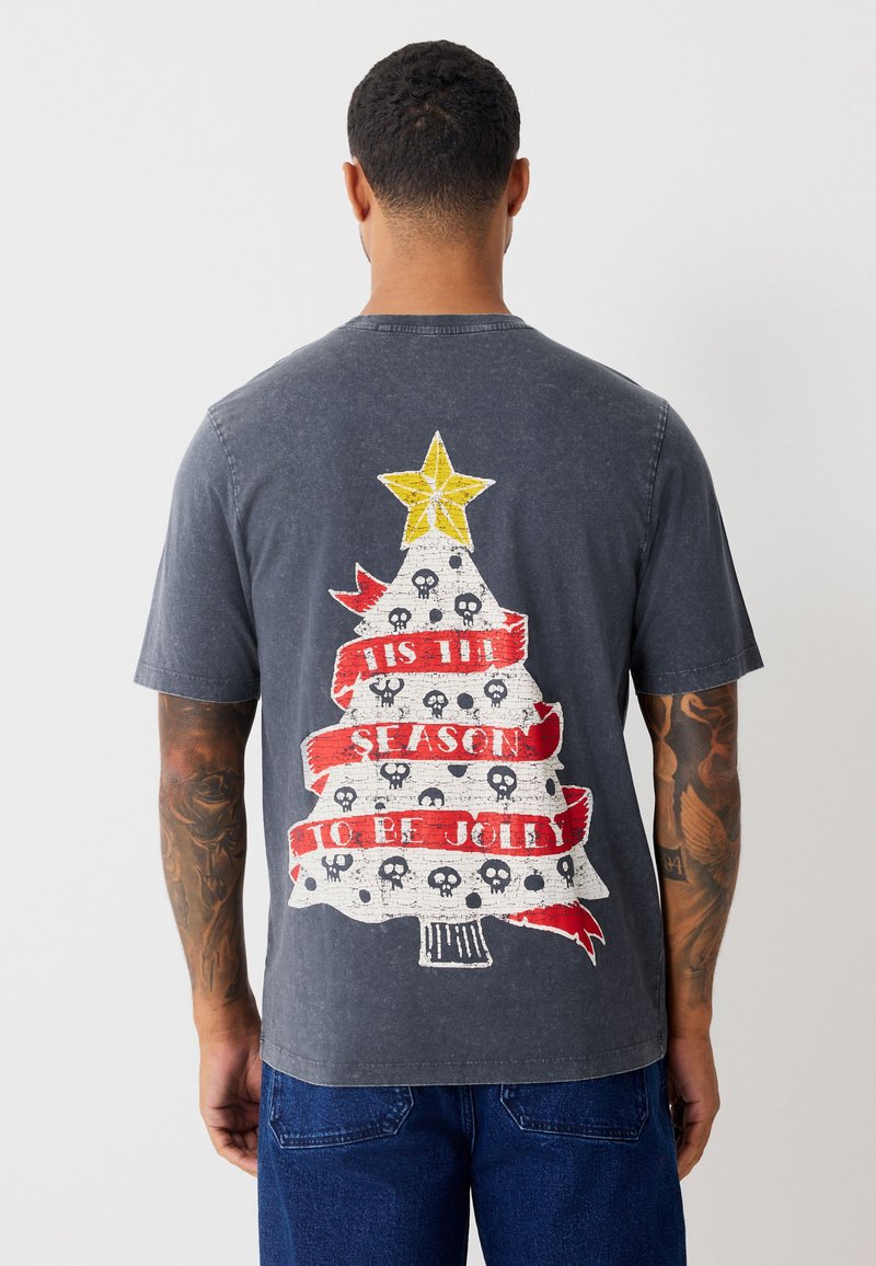 Dark gray T-shirt featuring a graphic of a Christmas tree with a yellow star, red ribbons, and skull accents, printed on the back.