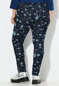 Denim legging met een donkerblauwe basis met een sterrenpatroon in lichtblauw. Het ontwerp heeft een licht vervaagde, versleten textuur.