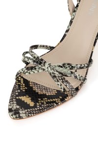 Szpilka z ostrym noskiem, wzór zielono-czarnej skóry węża, beżowe wnętrze, paski skrzyżowane i związane kokardą wokół kostki.