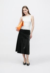 White ribbed tank top, black faux leather midi skirt, orange clutch bag, and black flats. Smooth textures and contrasting colors.
