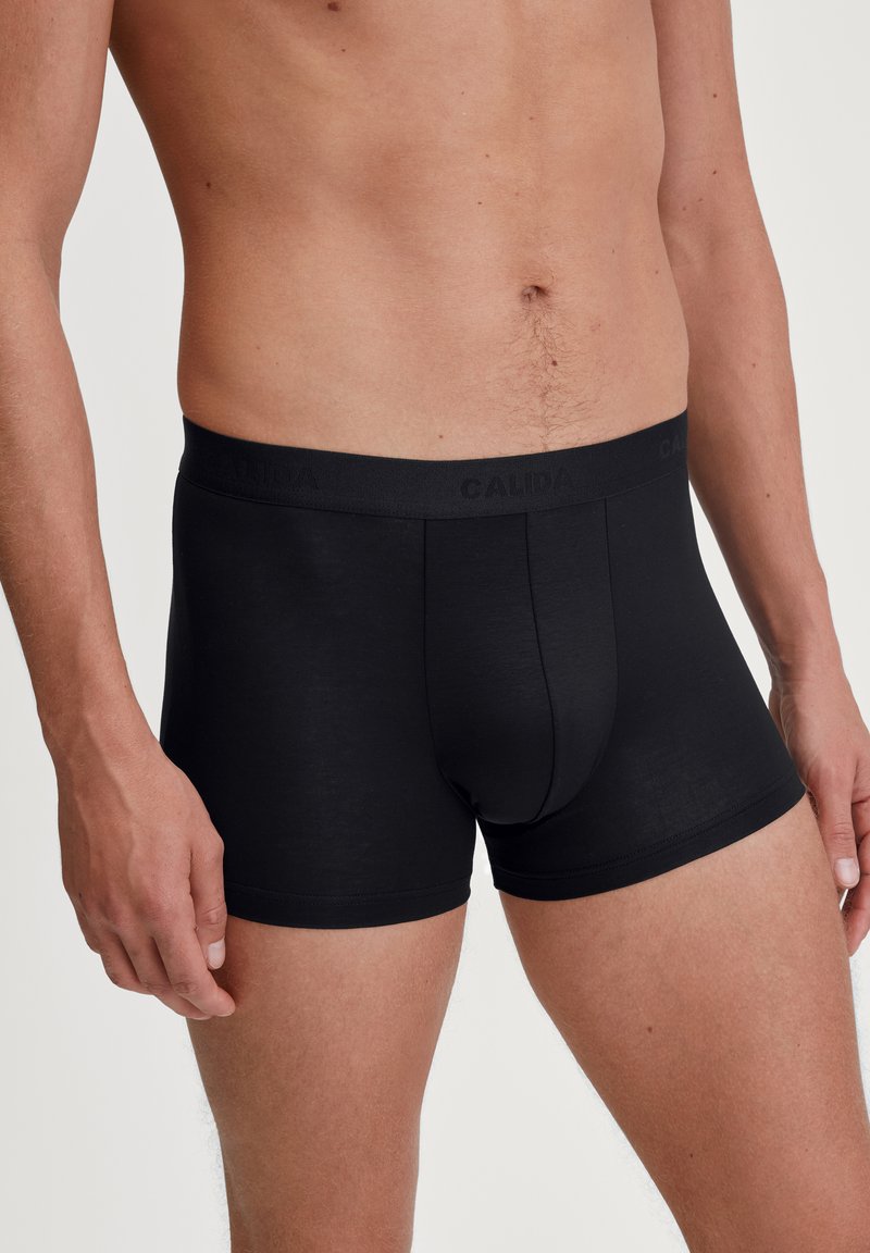 Zwarte boxershorts van een zachte stof. Elastische tailleband met "CALIDA" merknaam. Strakke pasvorm en gladde textuur. Lengte tot halverwege de dij.