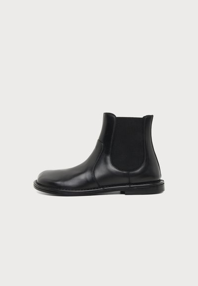 Bottine Chelsea noire en cuir avec panneau latéral élastique et petit talon, vue de profil droit sur fond blanc.