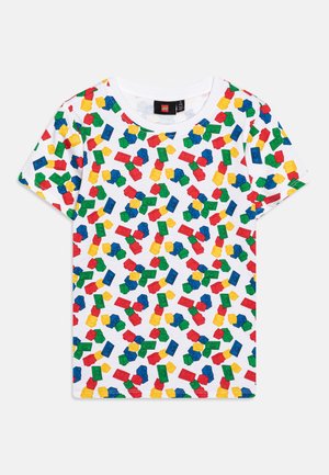 Hvid T-shirt med korte ærmer og et farverigt mønster af LEGO-klodser i rødt, blåt, grønt og gult over det hele.