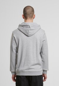 Sivi sweatshirt s kapuco s šnurovanjem, dolgimi rokavi, rebrastimi manšetami in pasom. Gladka, strukturirana tkanina z sproščenim krojem.