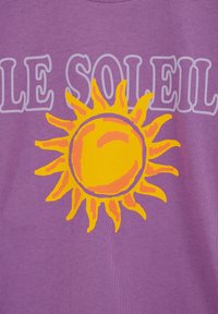 Geltona ir oranžinė saulės grafika su banguotais spinduliais centre ant violetinės medžiagos, iš dalies uždengta šviesiai violetiniais žodžiais „LE SOLEIL“.