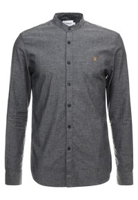 Chemise grise à manches longues avec col et boutons, présentant un petit logo brodé jaune sur la poitrine et des boutons noirs.