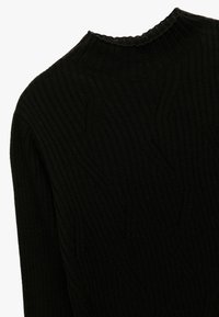 Zwarte ribbeltrui met een hoge kraag, textuurpatroon en een licht gerimpelde rand. Zachte gebreide stof met een egale afwerking.