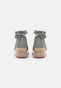 Baskets montantes grises avec une tige texturée, des accents de ruban noué et un talon tissé style espadrille. Semelle extérieure en caoutchouc de couleur claire.