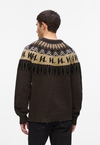 Pletena dukserica s teksturiranim smešnim telom, uzorkastim yoke u bež, crnoj i beloj boji, sa rebrastim manžetama i rubom.